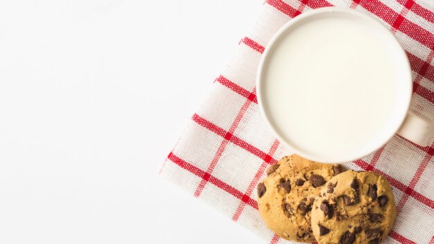 Leche con galletas en la servilleta sobre el fondo blanco