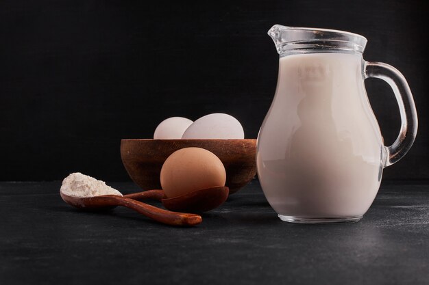 Leche, harina y huevos en espacio negro.