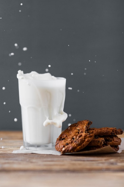 Leche salpicada en vaso con galletas