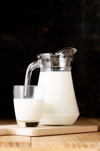 leche en vaso y jarra en mesa de madera