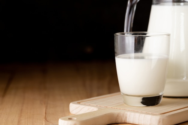 leche en vaso y jarra en mesa de madera