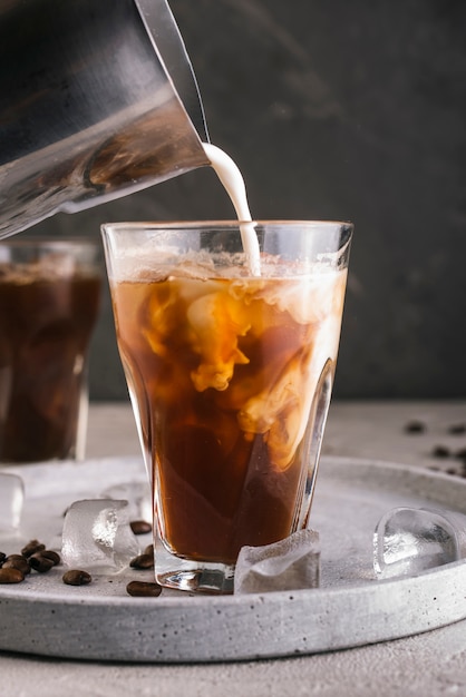 Leche vertiendo en vaso con café