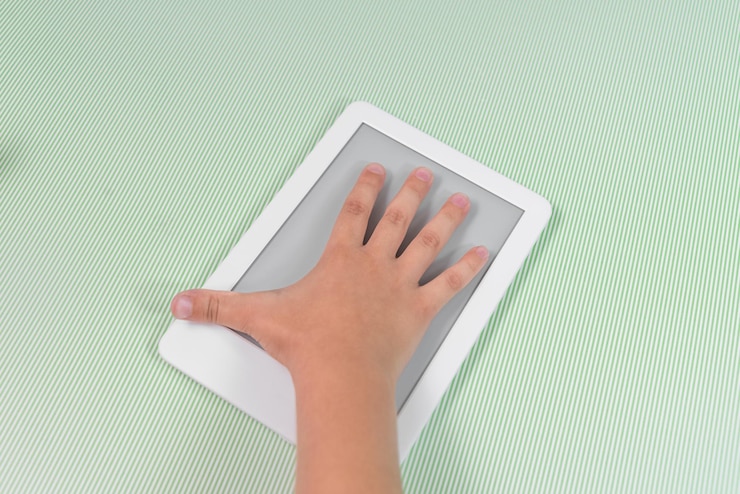 Foto gratuito lector de libros electrónicos sobre fondo verde sostenido por la mano de un niño