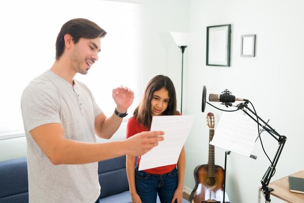 Lectura y memorización de la letra de la canción. Niña preadolescente aprendiendo una nueva canción con su profesor de música durante las lecciones de canto en casa