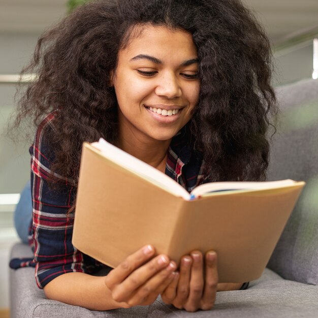 Lectura de niña sonriente de ángulo bajo