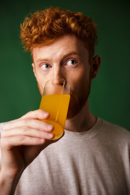 Lectura rizada barbudo hombre bebiendo jugo de naranja