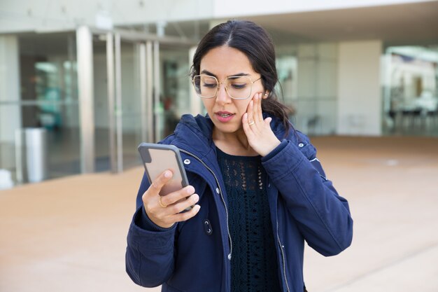 Lectura sorprendida de la muchacha en la pantalla del smartphone