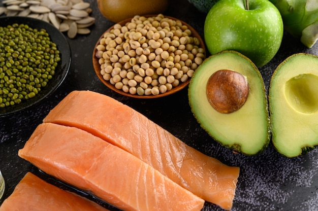 Foto gratuita legumbres, fruta y salmón colocados en un piso de cemento negro.