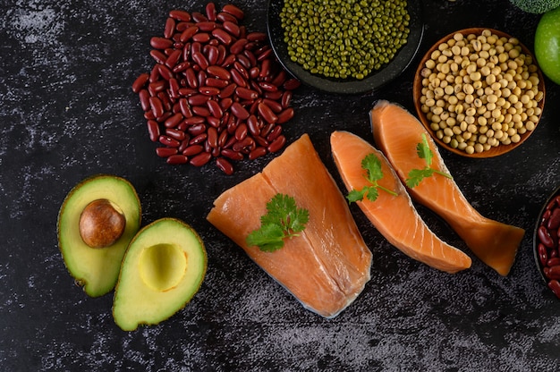 Foto gratuita legumbres, fruta y salmón colocados en un piso de cemento negro.