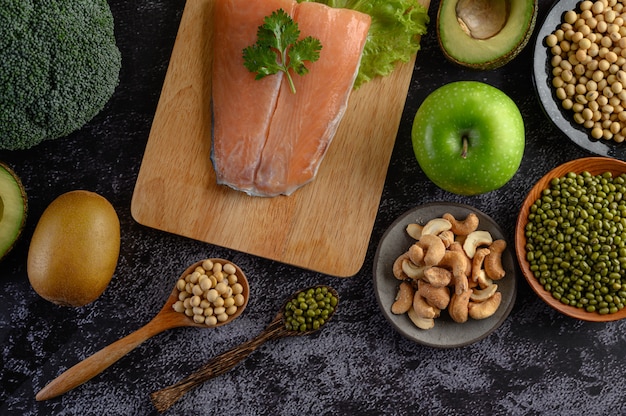 Foto gratuita legumbres, frutas y piezas de pescado de salmón en una tabla de cortar de madera.