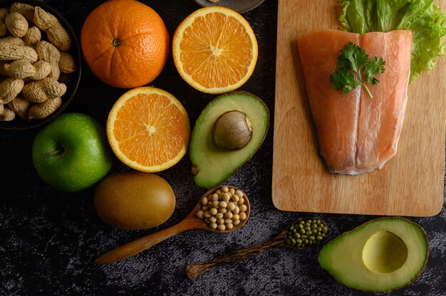 Legumbres, frutas y piezas de pescado de salmón en una tabla de cortar de madera.