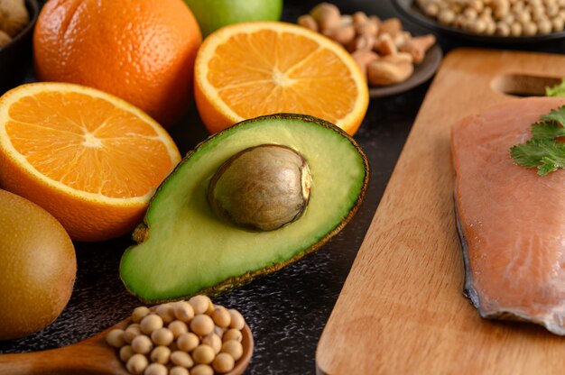 Legumbres, frutas y piezas de pescado de salmón en una tabla de cortar de madera.