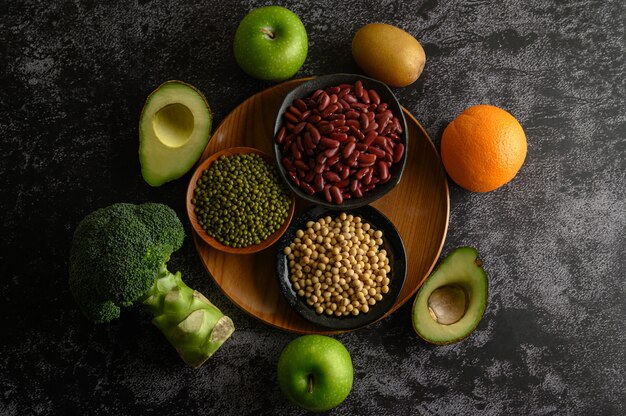 Foto gratuita legumbres y frutas en un piso de cemento negro.