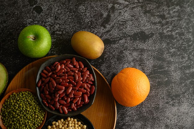 Legumbres y frutas en un piso de cemento negro.