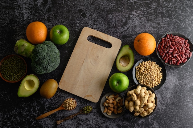 Foto gratuita legumbres y frutas en un piso de cemento negro.