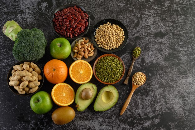 Legumbres y frutas sobre una superficie de piso de cemento negro.