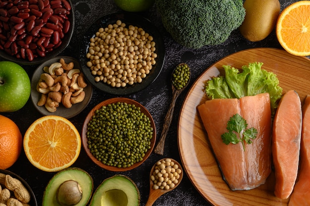 Legumbres, trozos de fruta y salmón en un plato de madera.