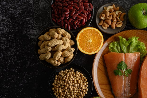 Legumbres, trozos de fruta y salmón en un plato de madera.