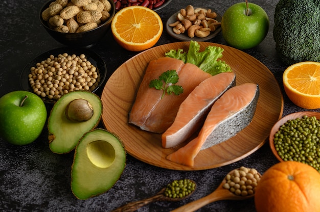 Legumbres, trozos de fruta y salmón en un plato de madera.