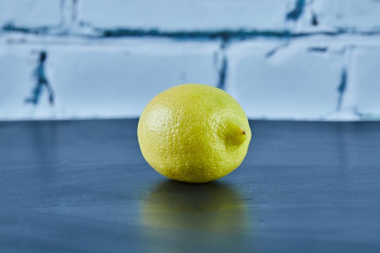 Photo Gratis lemon kuning berair utuh di atas permukaan biru