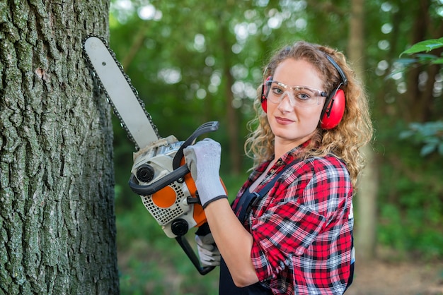 Leñador mujer cortando roble con motosierra en el bosque