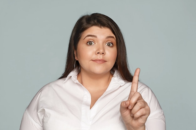 Foto gratuita lenguaje corporal. estricta y atractiva joven directora ejecutiva con sobrepeso con mejillas regordetas levantando las cejas y disgustada con resultados de trabajo ineficaces, reprendiendo a los empleados, agitando el dedo índice