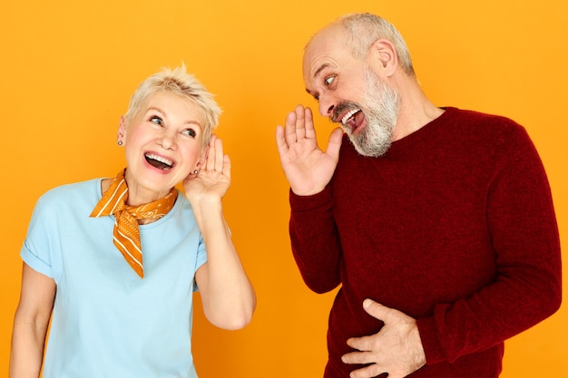 Foto gratuita lenguaje corporal. retrato de dos jubilados caucásicos ancianos divertidos con problemas de audición conversando, manteniendo las manos en la oreja y gritando, pero no pueden distinguir ninguna palabra. concepto de sordera