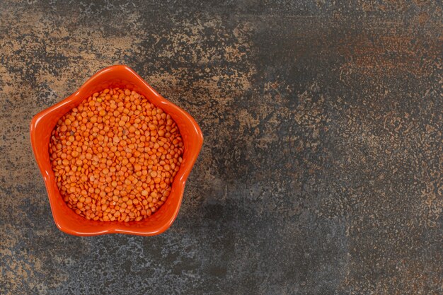 Foto gratuita lentejas rojas crudas en tazón de fuente naranja.