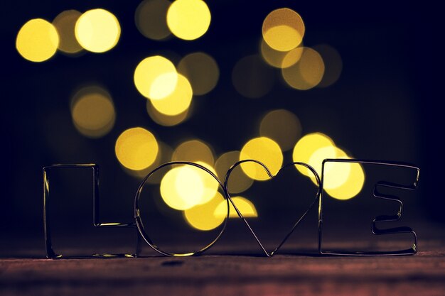 Letras metálicas con la palabra "love" con un efecto bokeh detrás