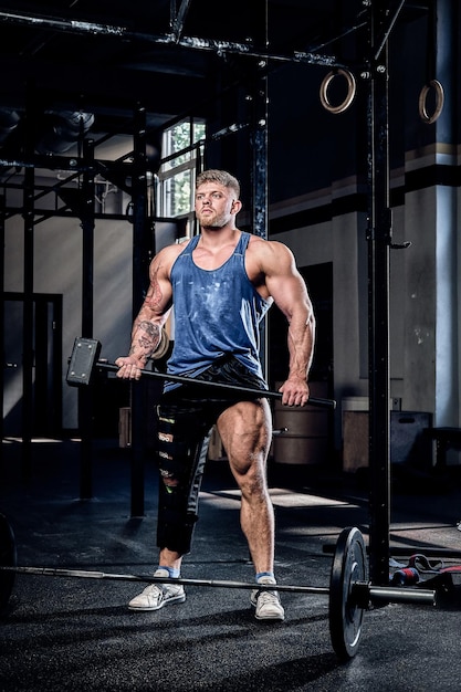 Levantador de potencia profesional con un vendaje en una pierna, sosteniendo un martillo deportivo, calentando antes del entrenamiento, recuperación de lesiones. Deporte, compromiso, motivación