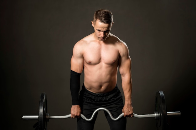 Levantamiento de pesas de hombre de alto ángulo en el gimnasio