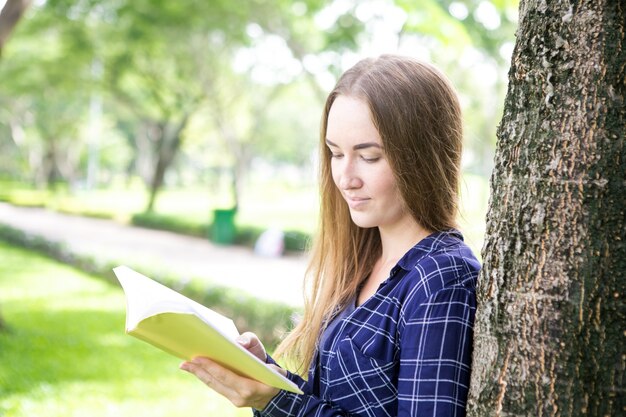 Libélula femenina pacífica que goza el leer en parque