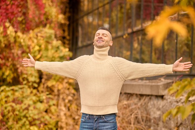 Libertad. Un hombre con un jersey de cuello alto beige en el parque de otoño