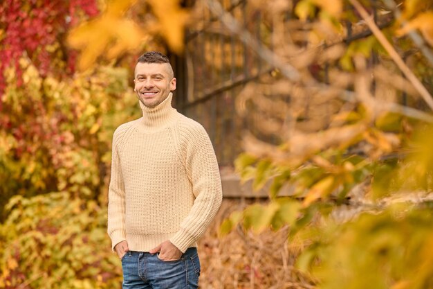 Libertad. Un hombre con un jersey de cuello alto beige en el parque de otoño
