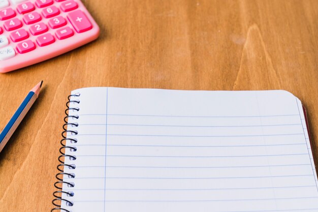 Libreta, lápiz y calculadora sobre mesa de madera