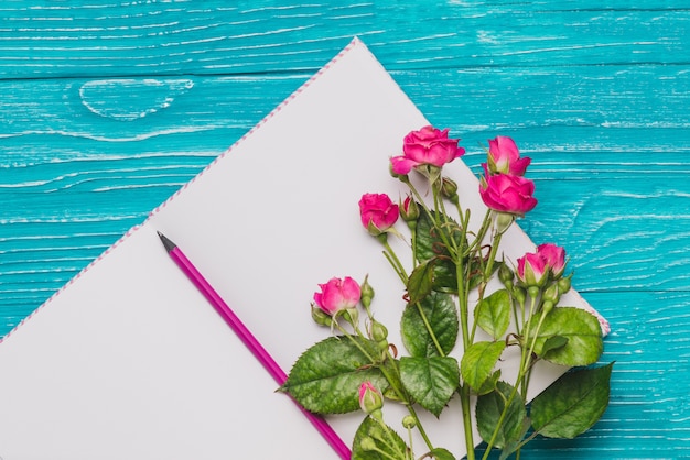 Foto gratuita libro abierto en blanco con lápiz y flores decorativas