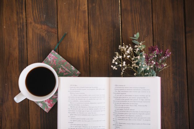 Libro abierto cerca de café y ramo