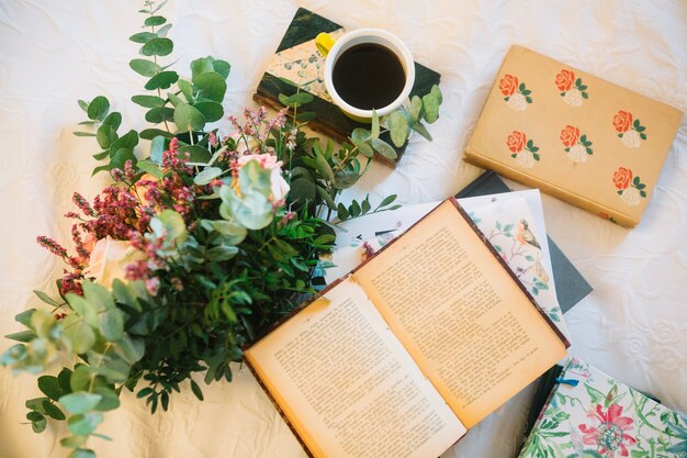 Libro abierto cerca de ramo y café