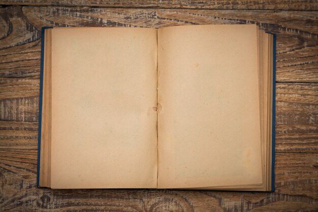 Libro antiguo abierto en una mesa de madera visto desde arriba