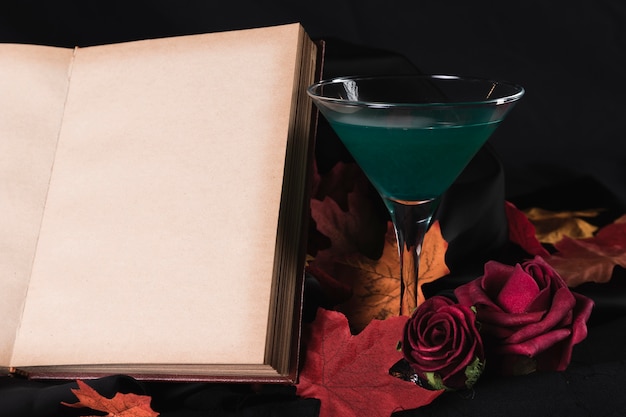 Libro con bebida verde y rosas