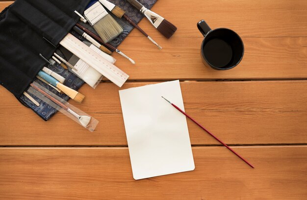 Libro blanco con pinceles en la mesa de madera