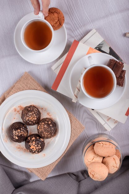 Libro, bocadillos dulces y una taza de té sobre la mesa.