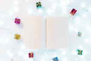 Foto gratuita libro de escritura entre regalos y luces de colores.