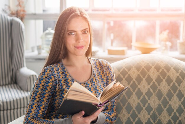 Libro de la explotación agrícola de la mujer bastante joven a disposición que mira la cámara