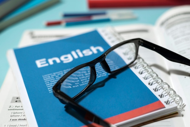 Foto gratuita libro de ingles con gafas en la mesa