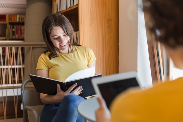 Foto gratuita libro de lectura adolescente cerca de amigo con tableta