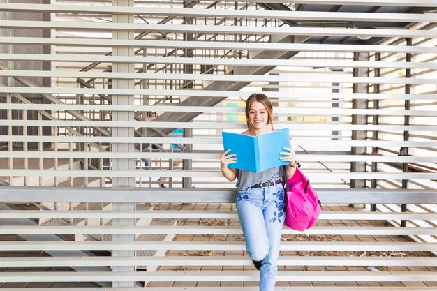 Libro de lectura alegre de la señora joven cerca de la pared