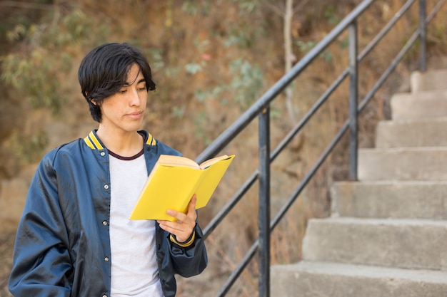 Foto gratuita libro de lectura asiático del adolescente en las escaleras