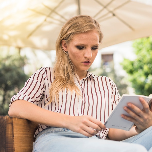 Libro de lectura atractivo de la mujer joven en al aire libre