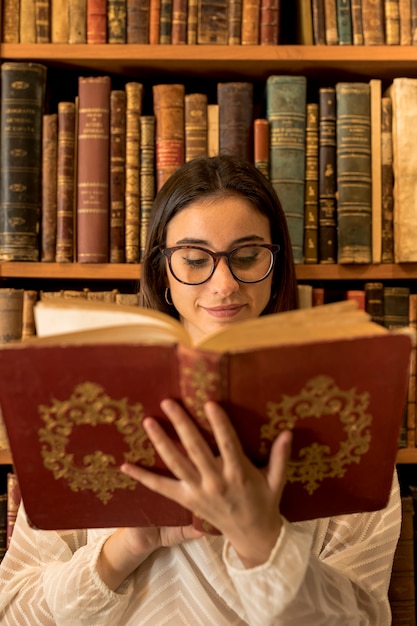 Libro de lectura bastante elegante de la mujer cerca del estante